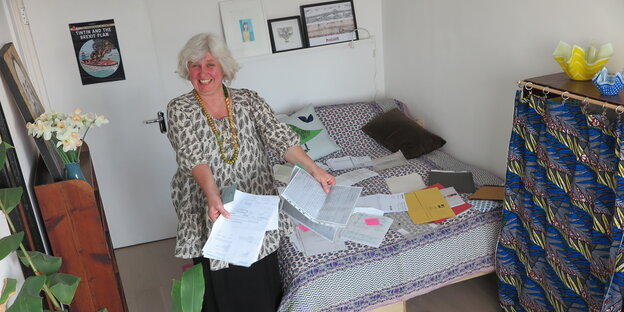 Elke Heckel in einem Zimmer mit Papieren am Boden Elke Heckel in einem Zimmer mit Papieren am Boden