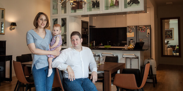 ein Paar steht im Wohnzimmer, die Frau hält ein Kind im Arm ein Paar steht im Wohnzimmer, die Frau hält ein Kind im Arm