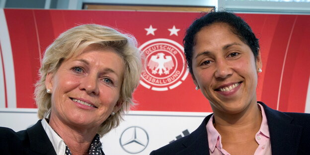 zwei lächelnde Frauen vor einem großen DFB-Logo zwei lächelnde Frauen vor einem großen DFB-Logo