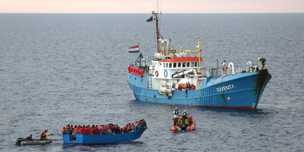 Ein blaues Holzboot neben einem blauen Schiff Ein blaues Holzboot neben einem blauen Schiff