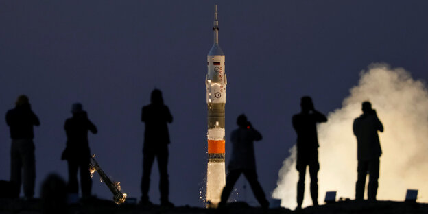 Rakete am Horizont, davor die Umrisse von Menschen Rakete am Horizont, davor die Umrisse von Menschen