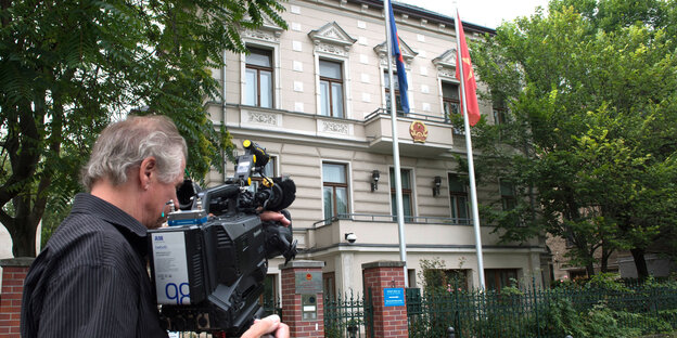 Ein Kameramann richtet seine Kamera auf ein Gebäude Ein Kameramann richtet seine Kamera auf ein Gebäude