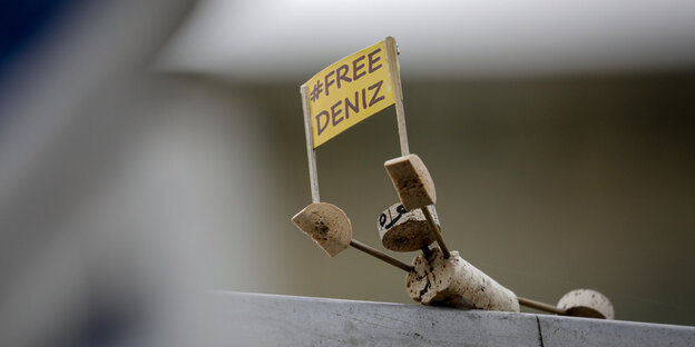 Eine Figur aus Korken hält ein Schild, auf dem „Free Deniz“ steht Eine Figur aus Korken hält ein Schild, auf dem „Free Deniz“ steht