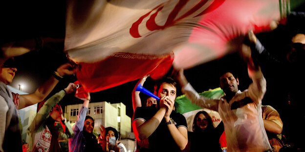 Iranische Fußballfans jubeln und schwenken eine Flagge Iranische Fußballfans jubeln und schwenken eine Flagge