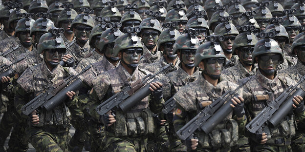 Nordkoreanische Soldaten mit schwarz getarnten Gesichtern marschieren mit schweren Waffen in Reih und Glied Nordkoreanische Soldaten mit schwarz getarnten Gesichtern marschieren mit schweren Waffen in Reih und Glied