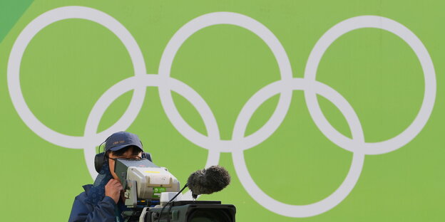 ein Kameramann vor Olympischen Ringen ein Kameramann vor Olympischen Ringen