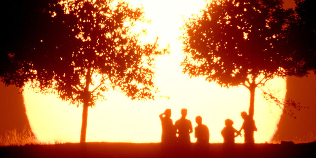 Menschen vor einer auf- oder untergehenden Sonne Menschen vor einer auf- oder untergehenden Sonne