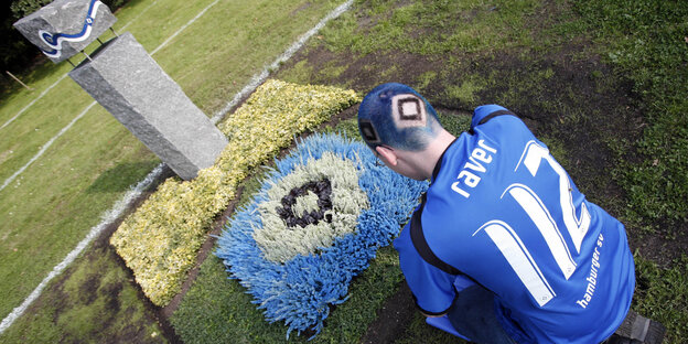 Ein HSV-Fan sitzt vor einem Grab mit HSV-Raute auf dem Altonaer Friedhof Ein HSV-Fan sitzt vor einem Grab mit HSV-Raute auf dem Altonaer Friedhof