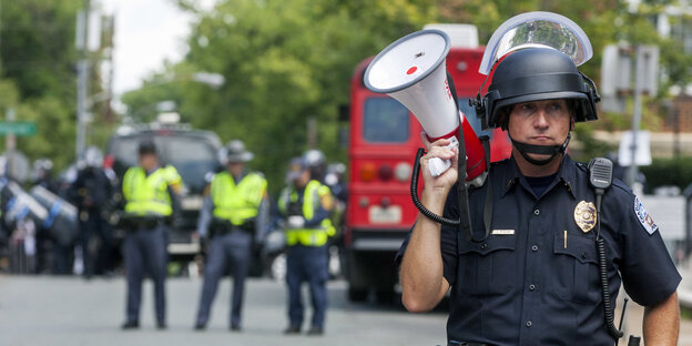 Ein Polizist hält ein Megafon Ein Polizist hält ein Megafon