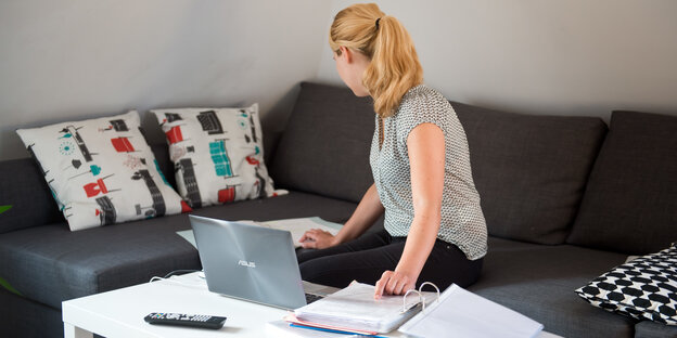 Eine Frau sitzt auf dem Sofa und arbeitet an einem Laptop. Eine Frau sitzt auf dem Sofa und arbeitet an einem Laptop.