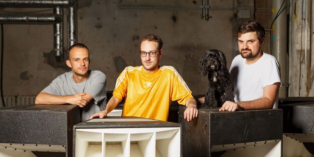 Drei Männer und ein Hund hinter Lautsprecherboxen Drei Männer und ein Hund hinter Lautsprecherboxen