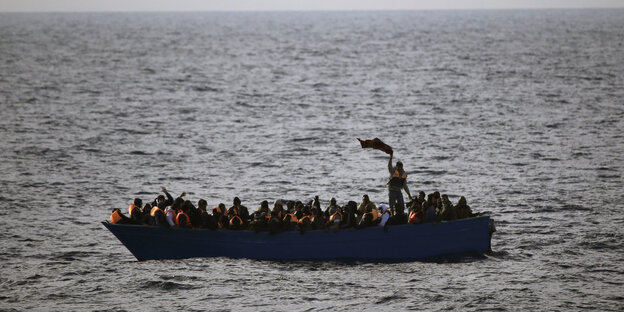 Ein Boot auf hoher See, darin viele Menschen mit Schwimmwesten Ein Boot auf hoher See, darin viele Menschen mit Schwimmwesten
