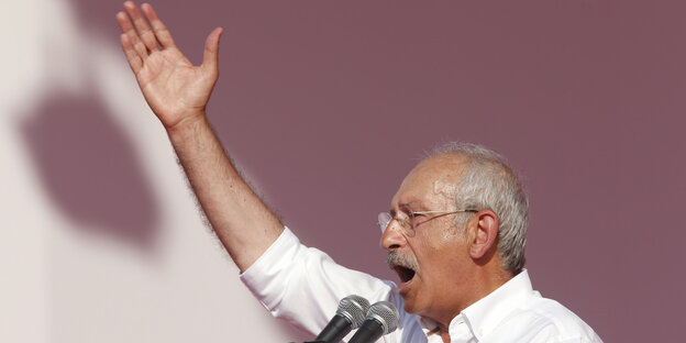 Profilbild eines Mannes. Er hebt seinen Arm nach oben und spricht in zwei Mikrofone. Profilbild eines Mannes. Er hebt seinen Arm nach oben und spricht in zwei Mikrofone.