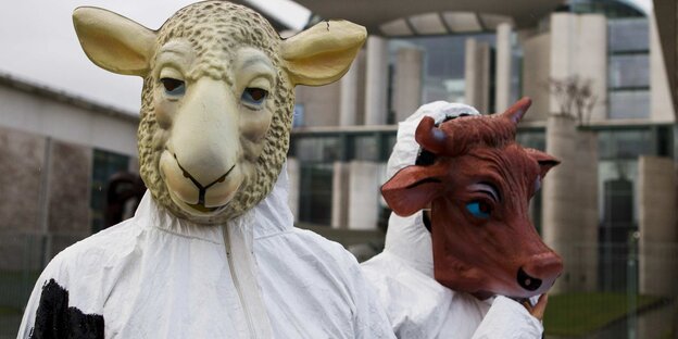 zwei Menschen in Schutzanzügen, einer mit Schafs-, der andere mit Rindermaske zwei Menschen in Schutzanzügen, einer mit Schafs-, der andere mit Rindermaske