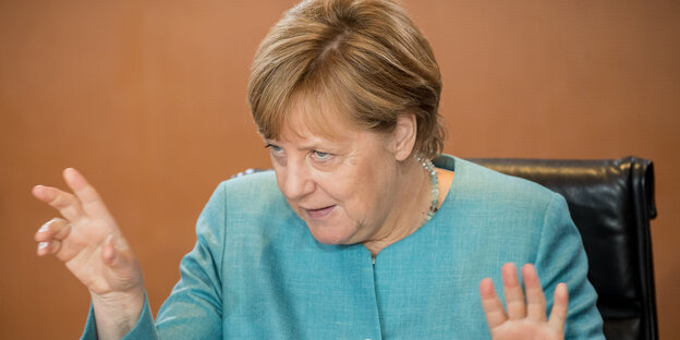 Angela Merkel hebt beide Hände und krallt die Finger Angela Merkel hebt beide Hände und krallt die Finger