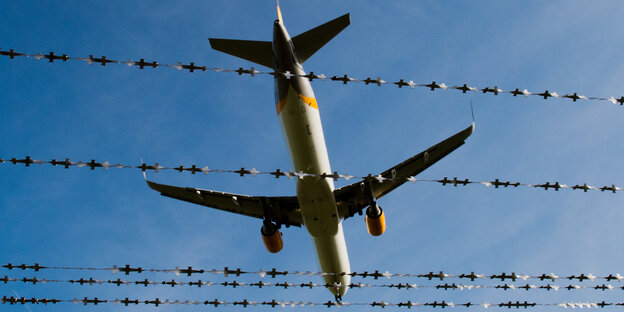 Ein Flugzeug über Stacheldrahtzaun Ein Flugzeug über Stacheldrahtzaun