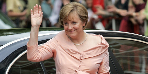 Angela Merkel steigt aus einem Auto und hebt den Arm zum Gruß Angela Merkel steigt aus einem Auto und hebt den Arm zum Gruß