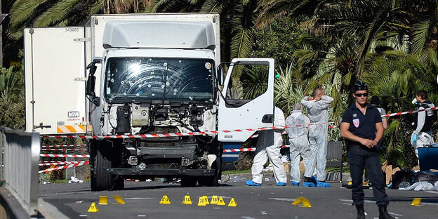 Ein stark beschädigter LKW, davor ein Polizist