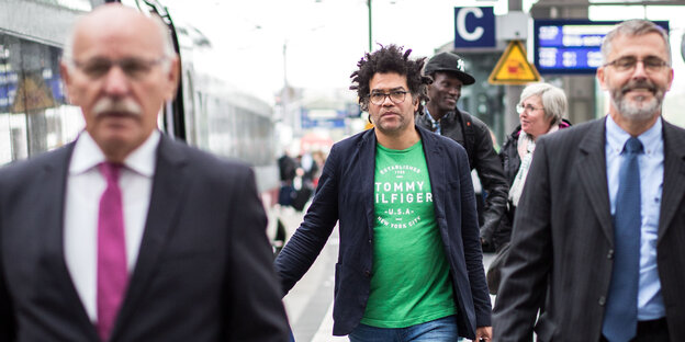 Ijoma Mangold geht in grünem T-Shirt und Jackett an einem Bahnsteig entlang Ijoma Mangold geht in grünem T-Shirt und Jackett an einem Bahnsteig entlang