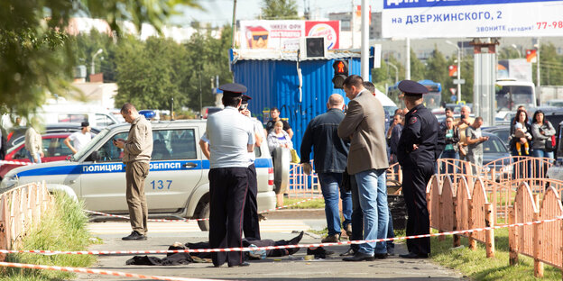 Polizisten stehen am 19.08.2017 in Surgut (Russland) an dem Ort eines Messerangriffs neben einer auf dem Boden liegenden Person. Polizisten stehen am 19.08.2017 in Surgut (Russland) an dem Ort eines Messerangriffs neben einer auf dem Boden liegenden Person.