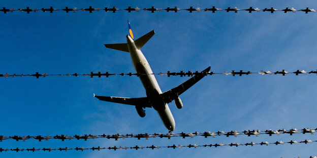 Ein Flugzeug, durch einen Stacheldrahtzaun gesehen Ein Flugzeug, durch einen Stacheldrahtzaun gesehen