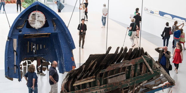 Teile eines zerbrochenen Bootes hängen in einer Ausstellungshalle Teile eines zerbrochenen Bootes hängen in einer Ausstellungshalle