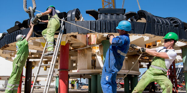 Männer bauen an einem Schneiderad, das für eine Tunnelbohrmaschine gedacht ist Männer bauen an einem Schneiderad, das für eine Tunnelbohrmaschine gedacht ist