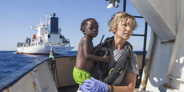 Eine Krankenschwester hält ein Kind auf dem Arm auf einem Schiff Eine Krankenschwester hält ein Kind auf dem Arm auf einem Schiff