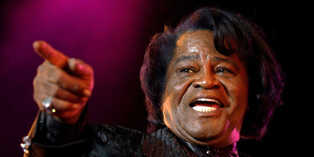 James Brown zeigt mit dem Finger in die Ferne James Brown zeigt mit dem Finger in die Ferne