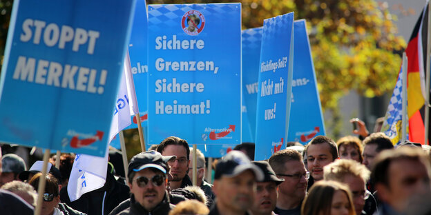 Menschen halten Plakate mit AfD-Slogans in die Höhe