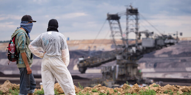 Zwei Braunkohlegegner stehen erhöht und blicken auf das das Braunkohlekraftwerk herab