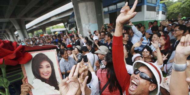 Yingluck Shinawatras Anhänger demonstrieren vor Gericht und halten ein Foto der Frau in den Händen Yingluck Shinawatras Anhänger demonstrieren vor Gericht und halten ein Foto der Frau in den Händen