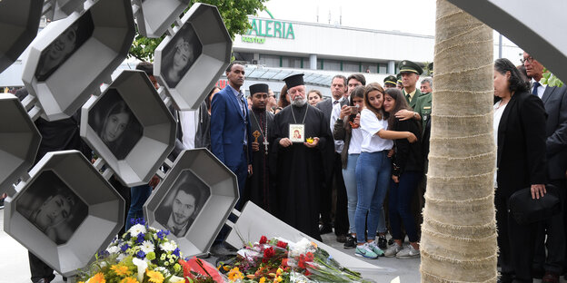 Menschen trauern vor einem Denkmal Menschen trauern vor einem Denkmal