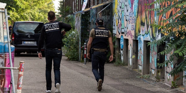 Zwei Polizisten vor einer Wand mit Graffiti Zwei Polizisten vor einer Wand mit Graffiti