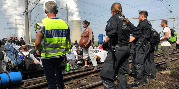 Menschen sitzen auf Bahngleisen Menschen sitzen auf Bahngleisen
