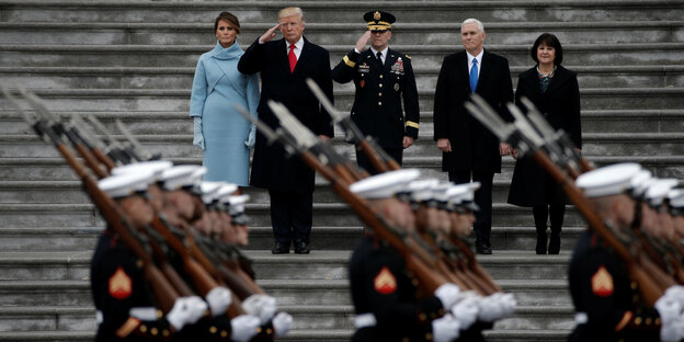 Soldaten in Paradeuniform marschieren an Trump und vier weiteren personen vorbei Soldaten in Paradeuniform marschieren an Trump und vier weiteren personen vorbei