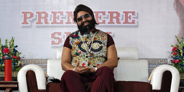 Dr. Gurmeet Ram Rahim Singh Ji Insam sitzt lächelnd auf einem Sofa