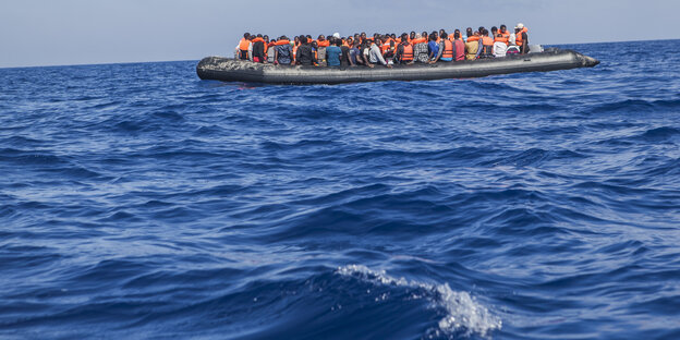 Ein Boot mit vielen Menschen darauf schwimmt im Meer Ein Boot mit vielen Menschen darauf schwimmt im Meer