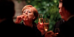 Angela Merkel trinkt aus einem Sektglas