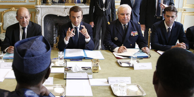 Viele Männer sitzen an einem Verhandlungstisch im Elysée-Palast Viele Männer sitzen an einem Verhandlungstisch im Elysée-Palast