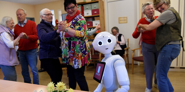 Ein Roboter und mehrere Menschenpaare beim Tanzen Ein Roboter und mehrere Menschenpaare beim Tanzen