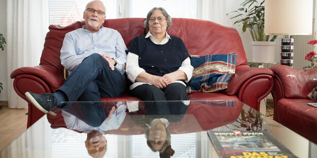 Ein älteres Ehepaar sitzt auf einem roten Sofa Ein älteres Ehepaar sitzt auf einem roten Sofa