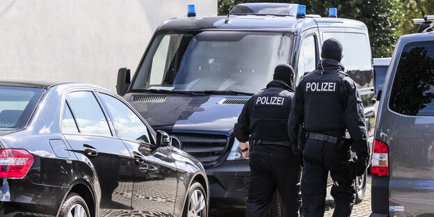 Zwei Polizisten gehen zwischen Autos durch