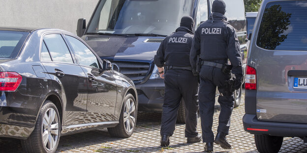 Polizisten einer Spezialeinheit zwischen Fahrzeugen Polizisten einer Spezialeinheit zwischen Fahrzeugen