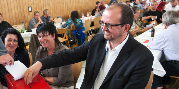Ein Mann im Anzug an einer Wahlurne Ein Mann im Anzug an einer Wahlurne