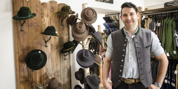 Ein Mann in bayerischer Tracht steht vor einer Hutwand Ein Mann in bayerischer Tracht steht vor einer Hutwand