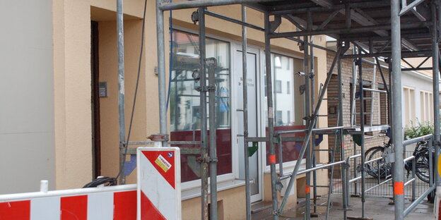 Ein Gerüst und eine Absperrung stehen vor einem Gebäude Ein Gerüst und eine Absperrung stehen vor einem Gebäude