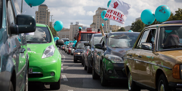 Blaue Luftballons sind an Autos befestigt. Aus einem hält jemand ein Banner mit der Aufschrift „Free Deniz“ Blaue Luftballons sind an Autos befestigt. Aus einem hält jemand ein Banner mit der Aufschrift „Free Deniz“