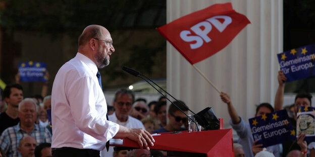 Martin Schulz in weißem Hemd an einem Rednerpult, hinten SPD-Anhänger Martin Schulz in weißem Hemd an einem Rednerpult, hinten SPD-Anhänger