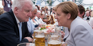 Ein Mann und eine Frau sitzen an einer langen Festtafel bei Bier und Brezn